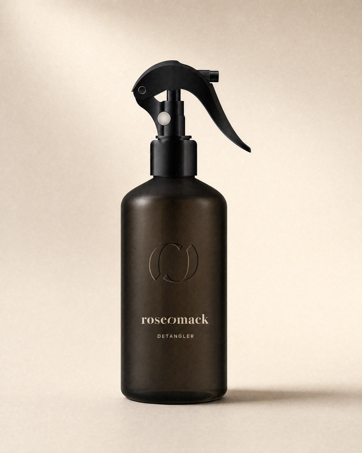 roseomack Detangler in a frosted dark brown bottle, the wordmark in beige under an embossed broken O