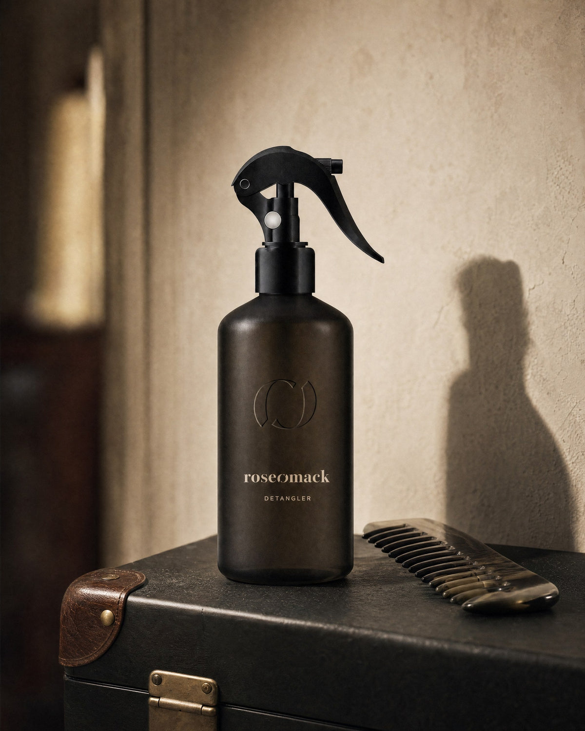 roseomack Detangler on a black leather trunk with brass fittings, a wide-tooth comb lying beside it
