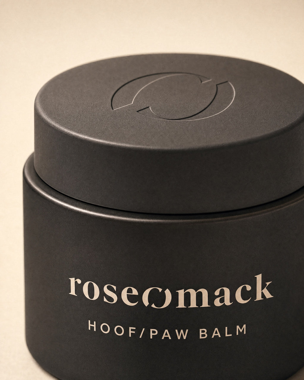 Close view of the matte black Hoof & paw balm lid, the roseomack broken O pressed into it