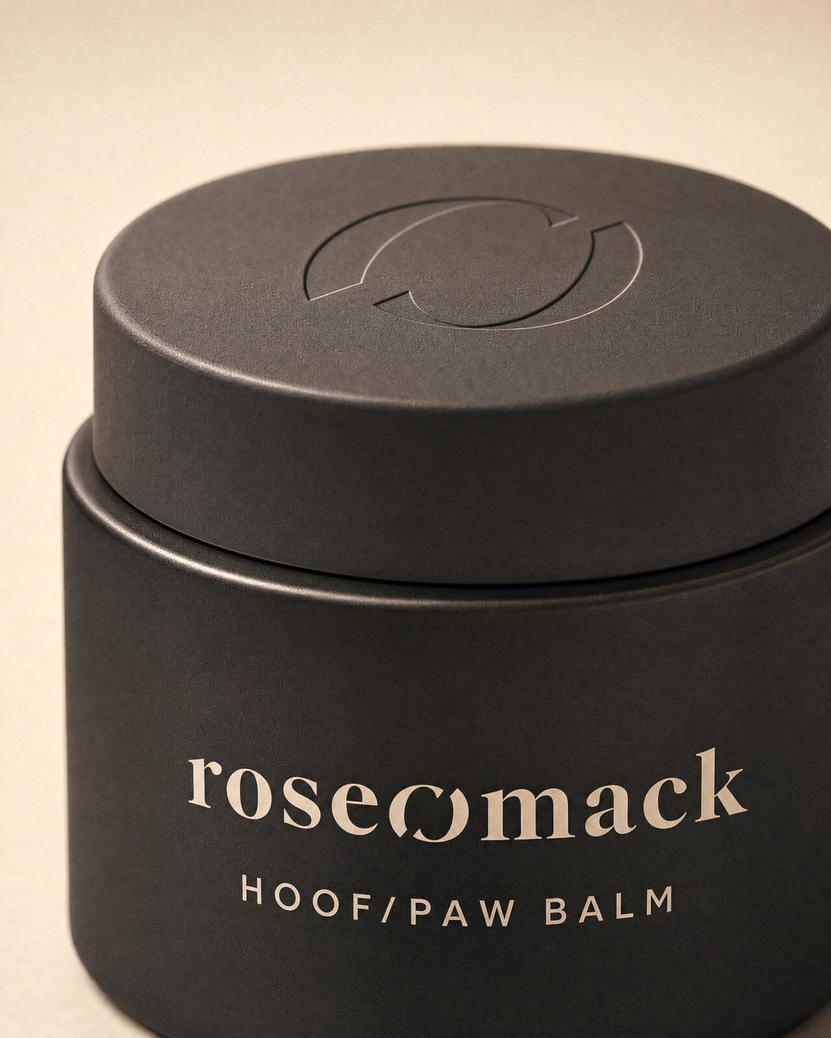 Close view of the matte black Hoof & paw balm lid, the roseomack broken O pressed into it