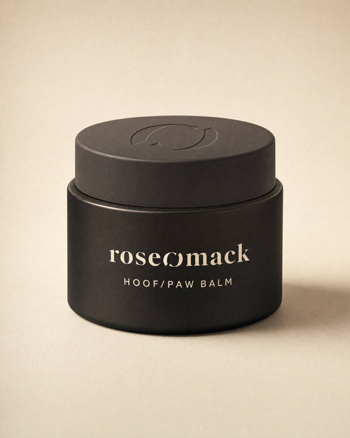 roseomack Hoof & paw balm jar in matte black, the wordmark and name printed in beige, on a sand backdrop
