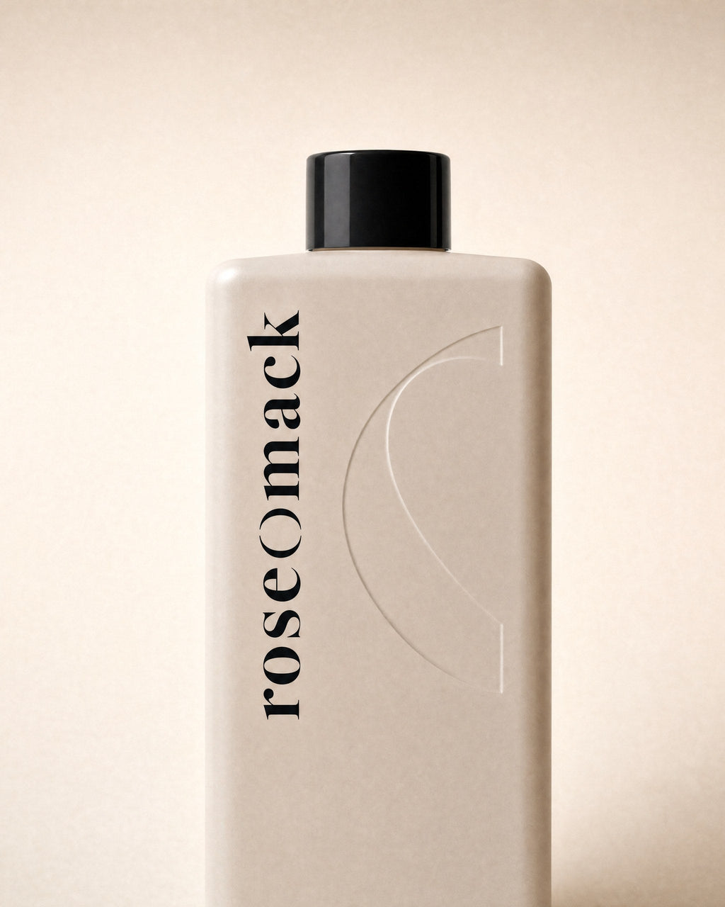 Close view of the vertical roseomack wordmark and embossed half O on the Shampoo & conditioner bottle