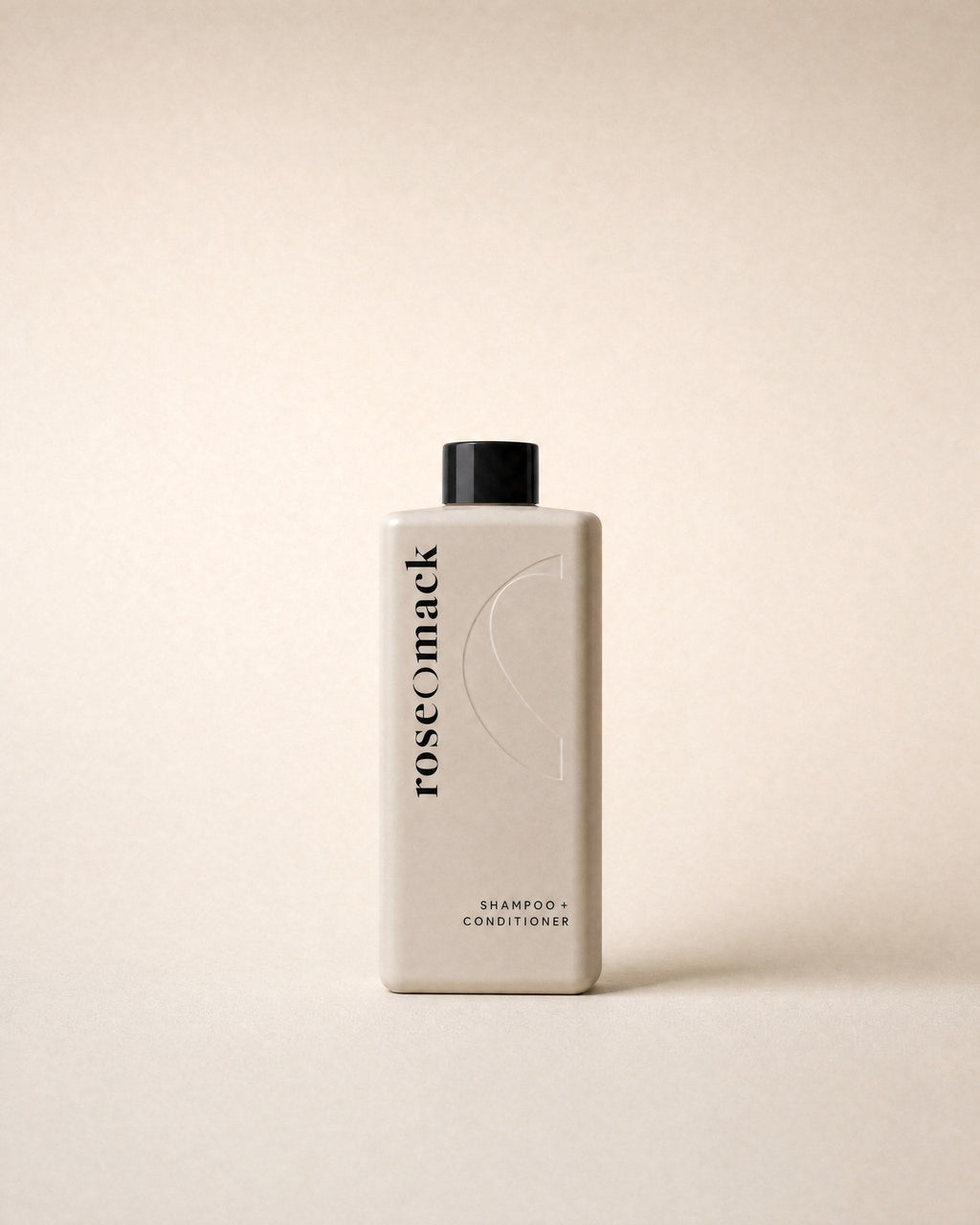 roseomack Shampoo & conditioner, a tall square greige bottle with a black cap, on a sand backdrop