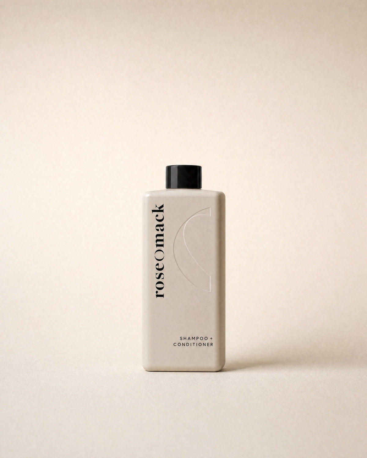 roseomack Shampoo & conditioner, a tall square greige bottle with a black cap, on a sand backdrop